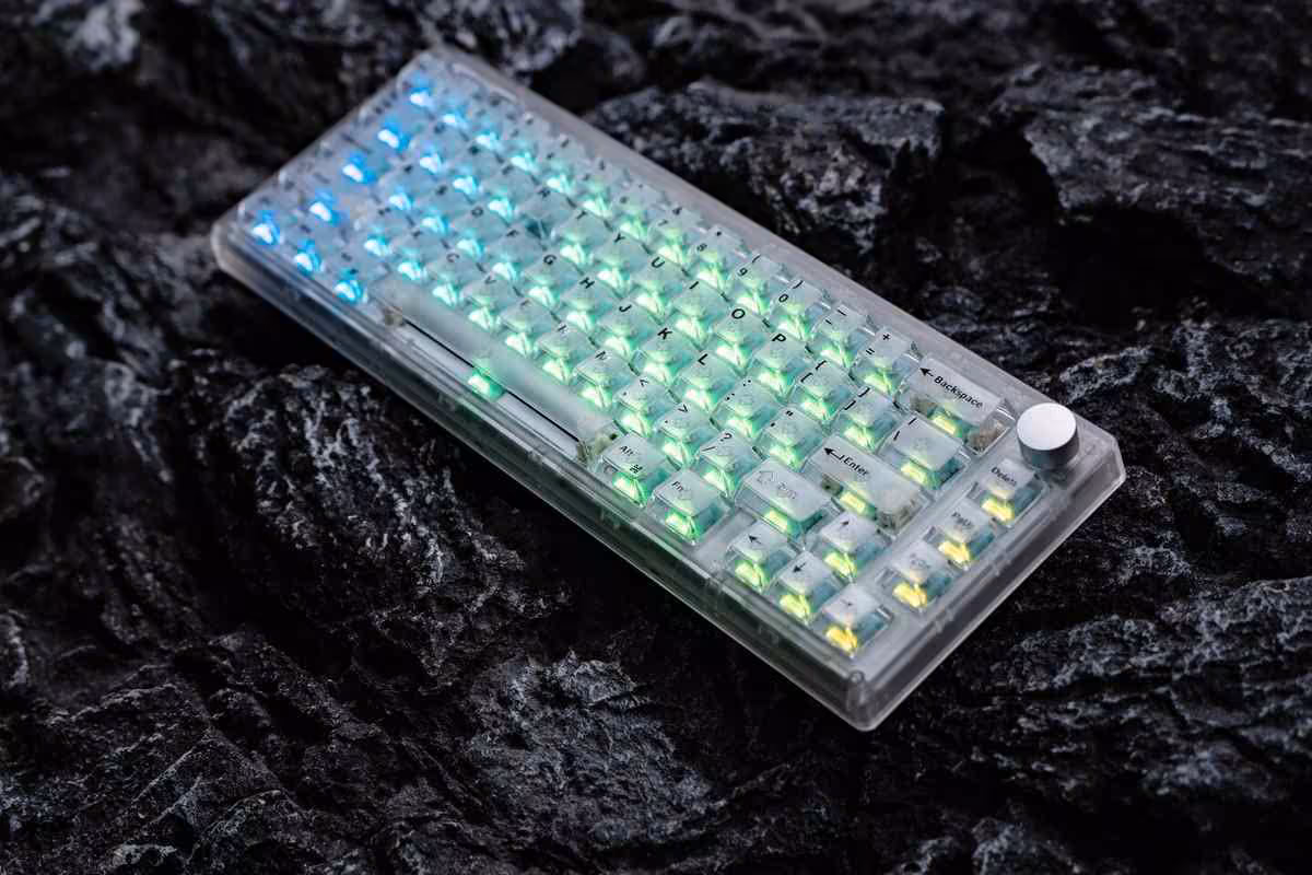 Clavier compact transparent à rétroéclairage RGB multicolore, posé sur roche sombre, vue produit principale