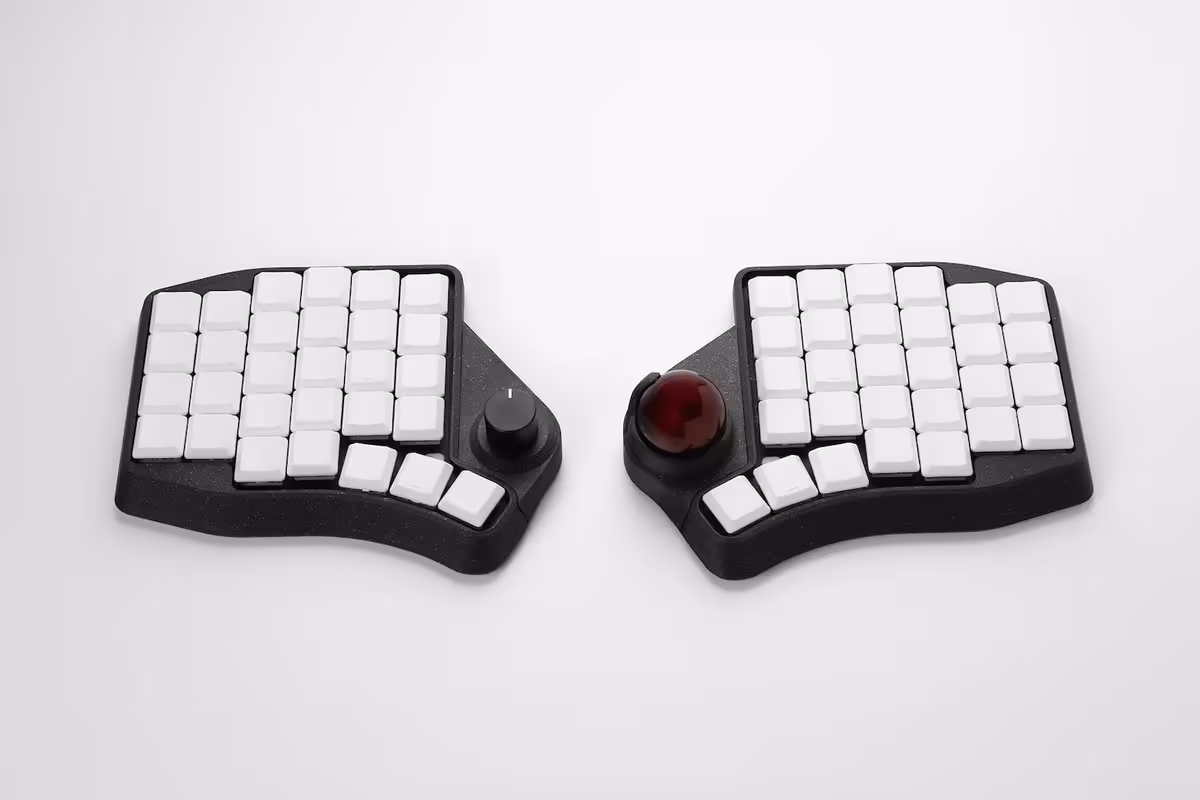 Clavier ergonomique scindé noir avec keycaps blancs et trackball rouge sur la moitié droite