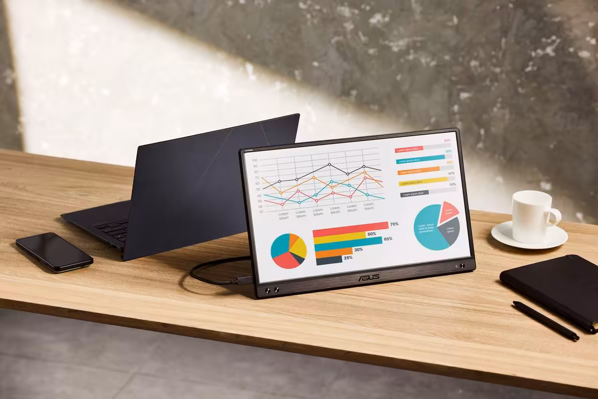 Écran portable ASUS ZenScreen affichant graphiques, connecté à un laptop noir sur bureau en bois.