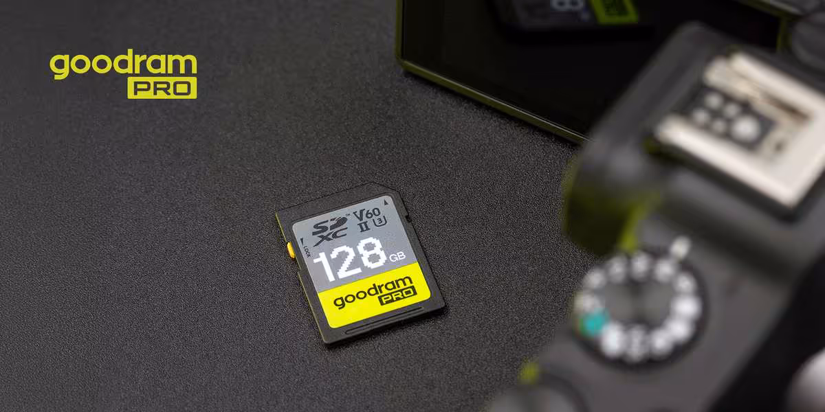 Carte SD Goodram PRO 128 Go UHS-II V60 sur fond sombre, avec appareil photo flou au premier plan