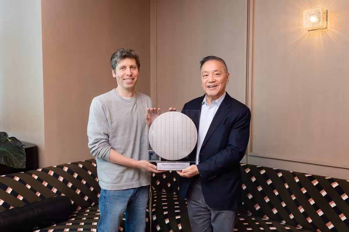Sam Altman et un homme tiennent le prototype OpenAI Jalapeño Intelligence Processor dans une pièce d’hôtel