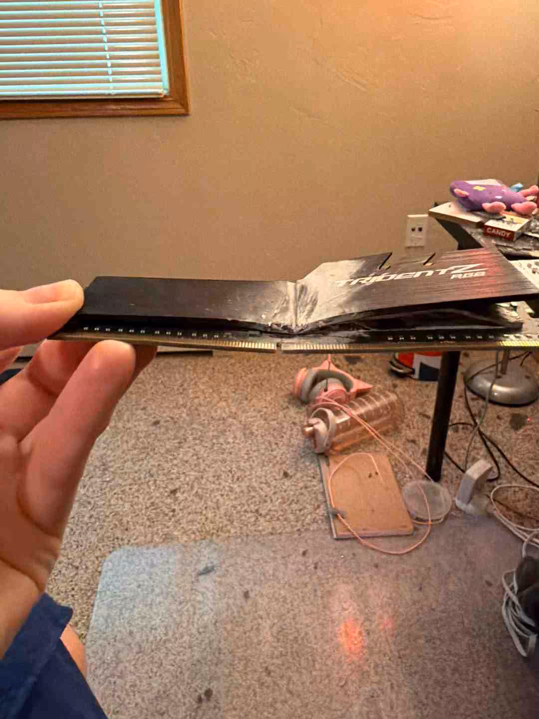 Carte mère avec module RAM tordu, éclairage faible, fond encombré
