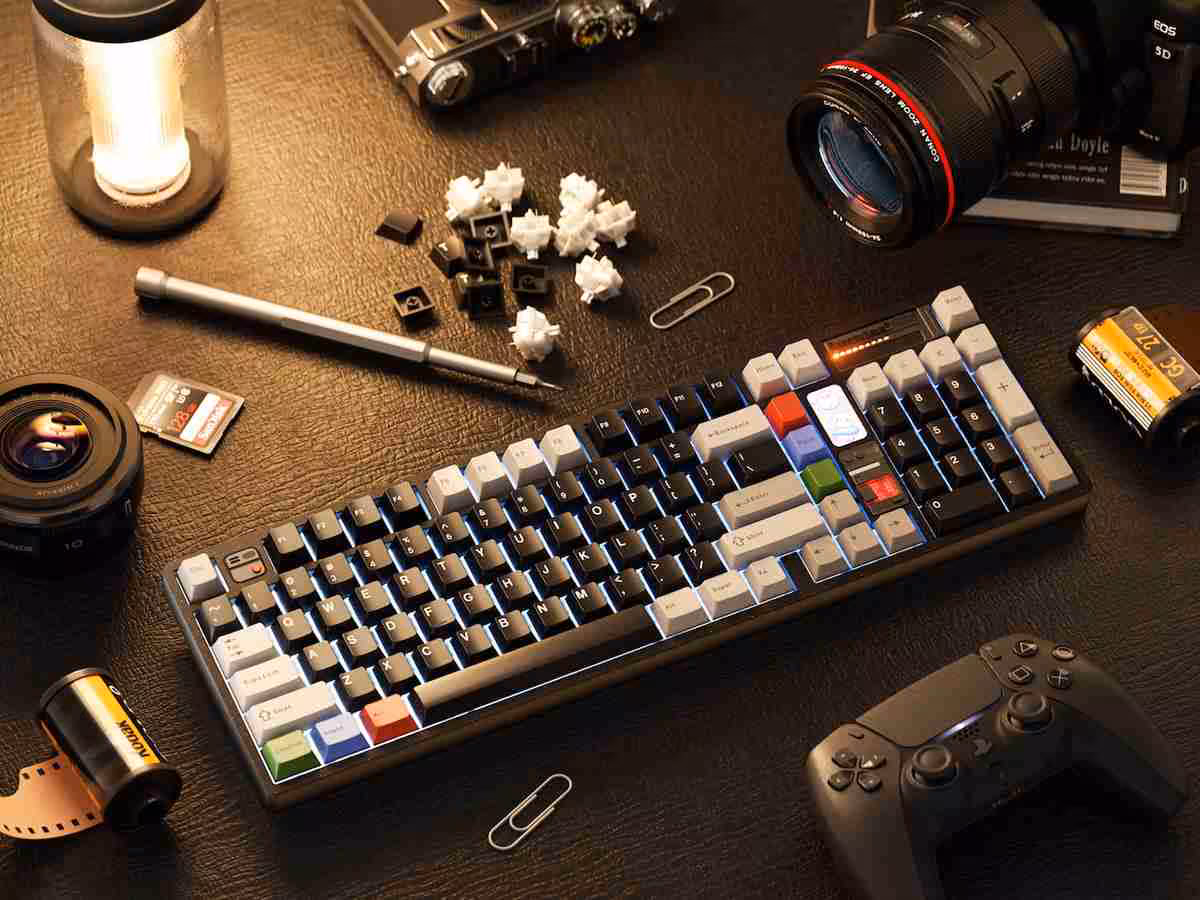 Clavier mécanique compact sur bureau, avec touches colorées, capuchons enlevés et accessoires photo autour.