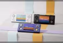 Trois consoles de jeu AYANEO Pocket MICRO 2, différentes couleurs, fond pastel neutre.