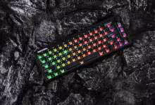 Clavier mécanique noir compact RGB arc-en-ciel, format 65 %, posé sur roche sombre
