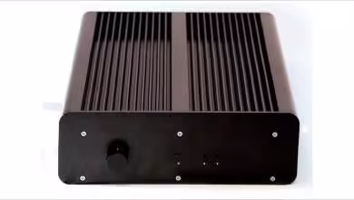 Boîtier noir avec ailettes de refroidissement, bouton avant, fond blanc, contrastes modérés