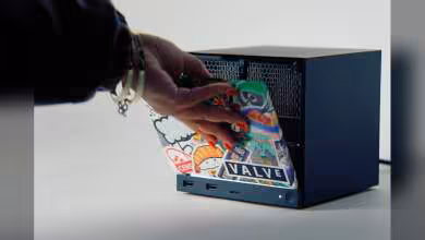 Main Mini PC noir avec façade bleue et logo VALVE, main insérant un boîtier Steam Deck stickerisé