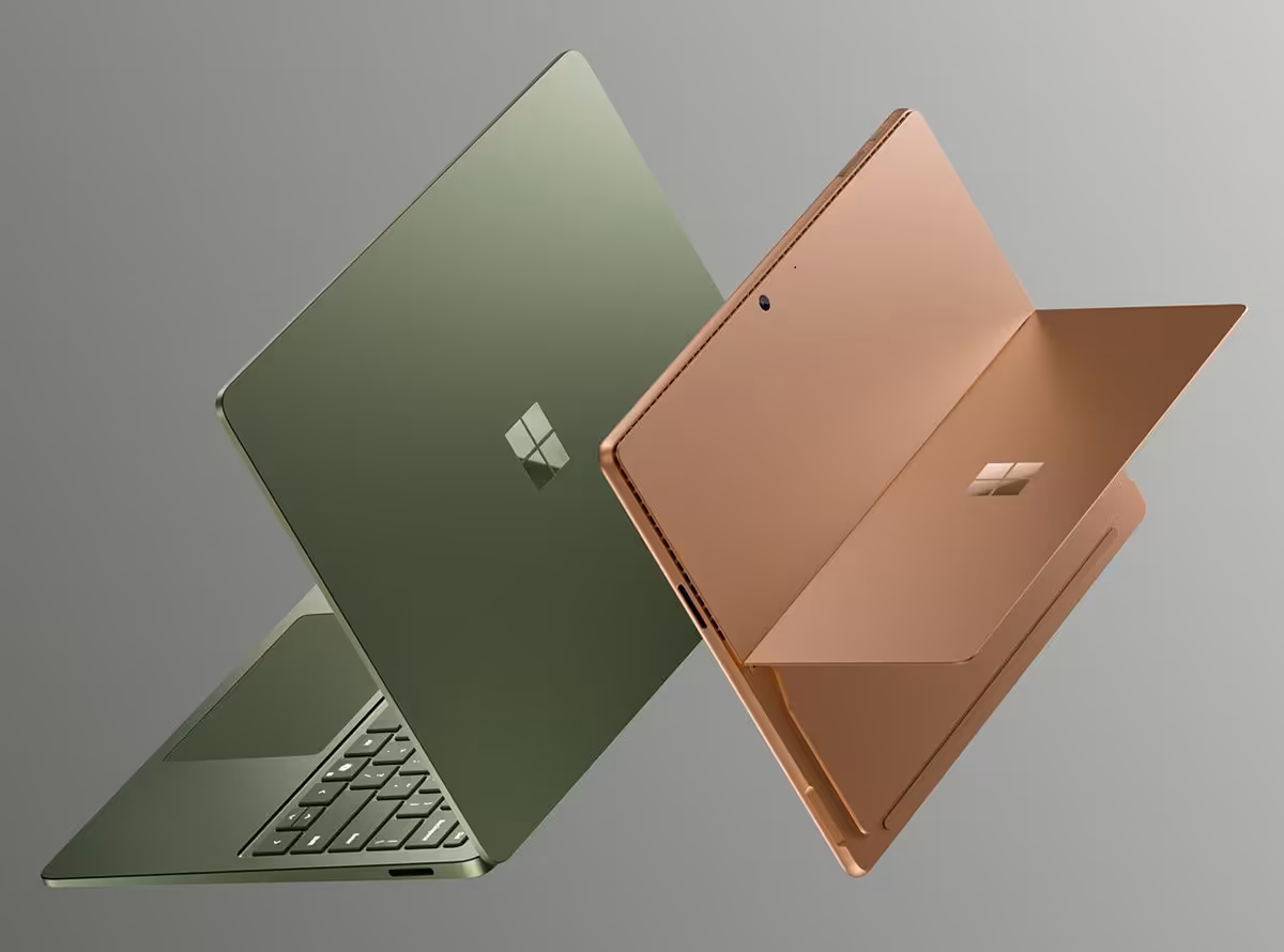 Deux ordinateurs portables Microsoft Surface en finition verte et cuivre, avec logo Windows visible sur le capot.