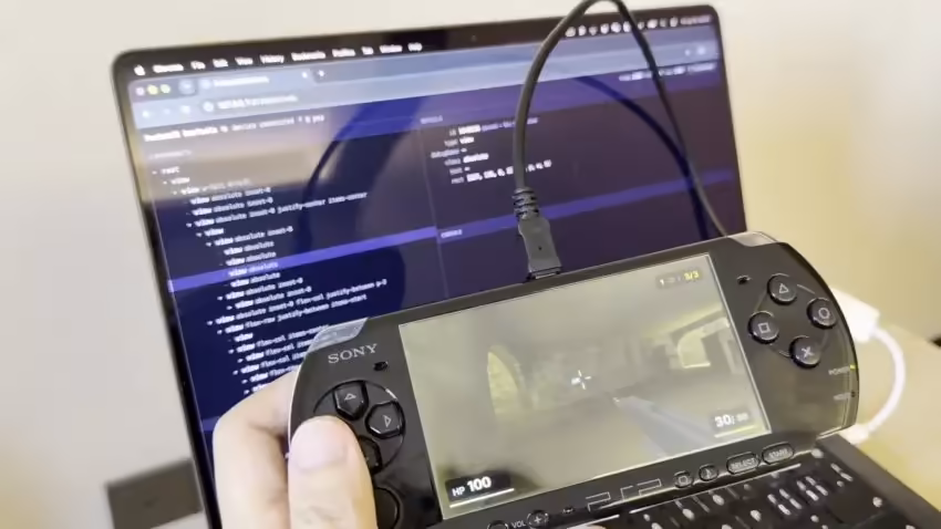 Photo d'une console portable Sony connectée à un ordinateur portable affichant du code.