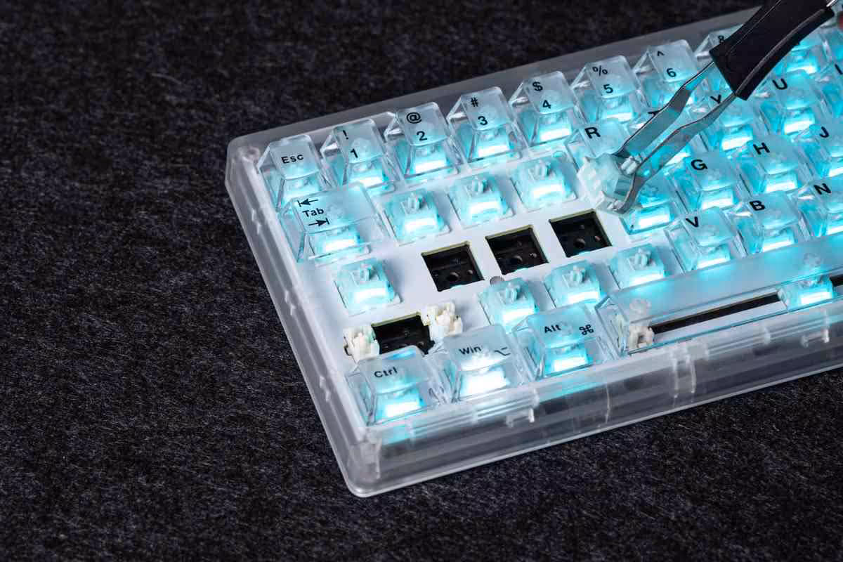 Clavier Epomaker transparent avec éclairage cyan, touches démontées et outil de maintenance visible