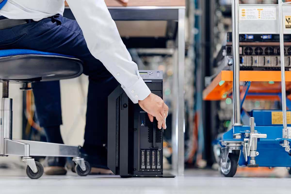 Technicien installant un serveur compact noir dans un environnement de datacenter industriel