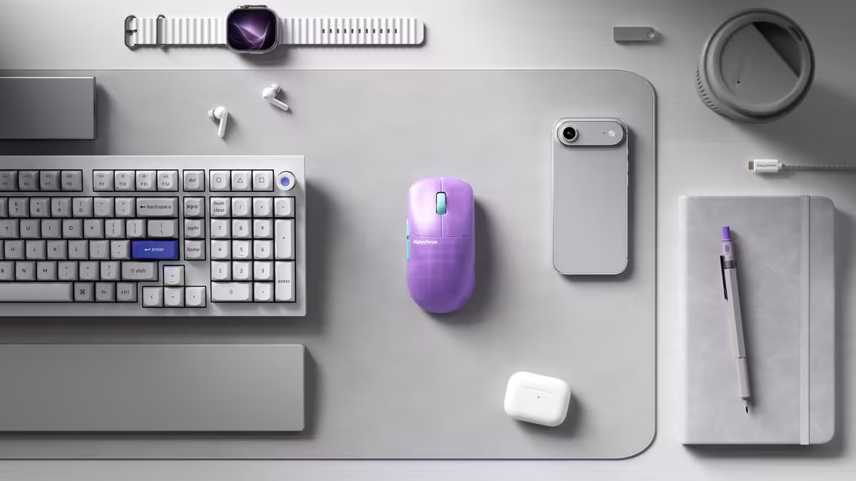 Bureau minimaliste avec clavier, souris Keychron G6 HE violette, smartphone, carnet et accessoires assortis