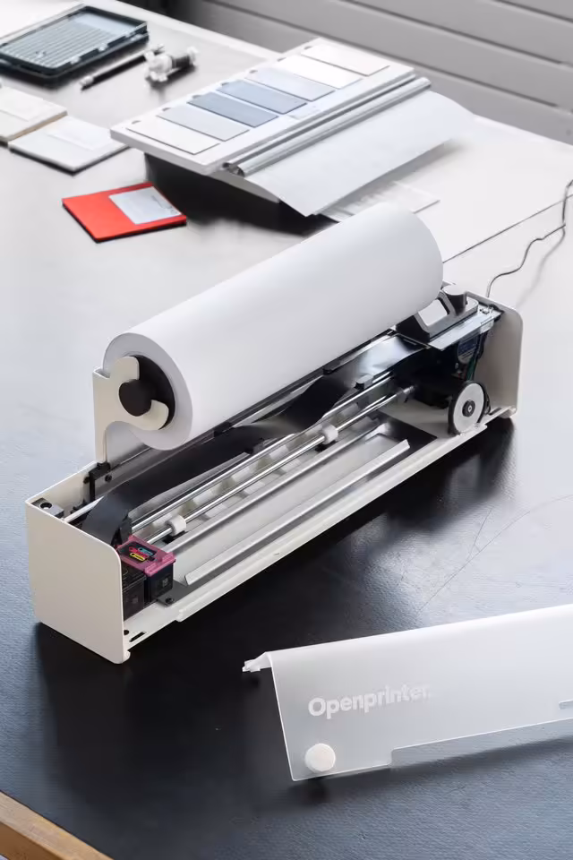 Open Printer : une imprimante open source, réparable et sans DRM bientôt sur CrowdSupply 2 Prototype OpenPrinter ouvert sur table, avec rouleau de papier, châssis métallique et capot démonté.