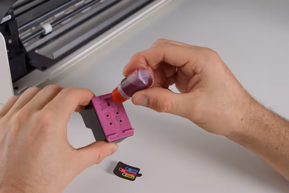 Open Printer : une imprimante open source, réparable et sans DRM bientôt sur CrowdSupply 5 Mains appliquant un liquide violet sur une pièce plastique rose près d’un châssis de machine.