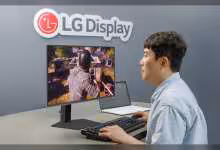 Écran LG Display avec jeu vidéo affiché, utilisateur avec clavier et ordinateur portable à côté.