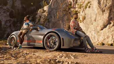 Supercar de course grise type Forza Horizon avec deux personnages assis, garée près d’une falaise rocheuse.