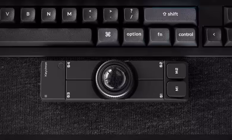 Keychron Nape Pro : le trackball sans fil arrive à 89,99 dollars hors Asie 1 Keychron Nape Pro noir posé sous un clavier, avec trackball central et boutons M1 M2