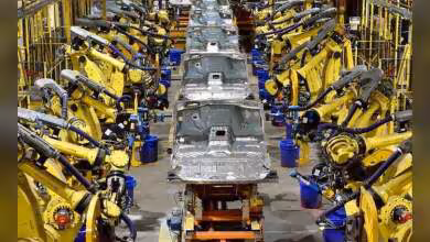 Chaîne d’assemblage automobile Ford avec nombreux bras robots jaunes autour d’une carrosserie métallique blanche