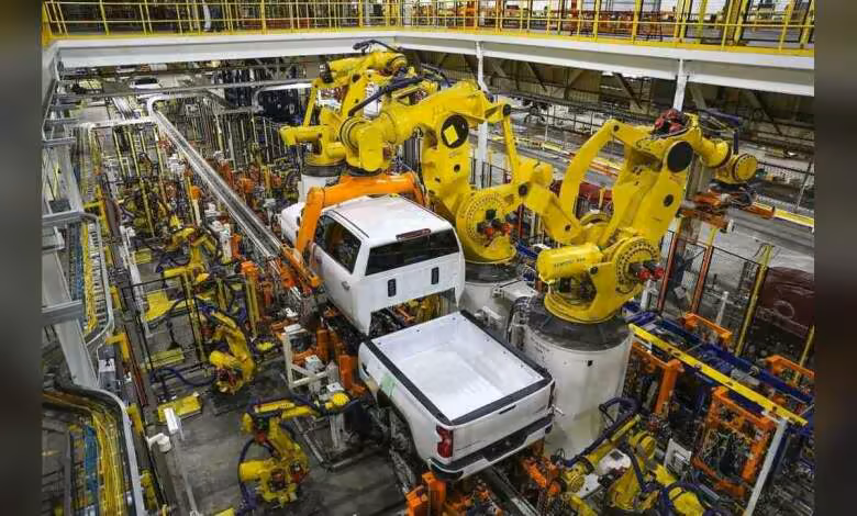 Micron GM : un accord stratégique pour verrouiller la mémoire auto sur le long terme 1 Chaîne d’assemblage automobile avec robots industriels jaunes manipulant une carrosserie et un pick-up blanc en usine
