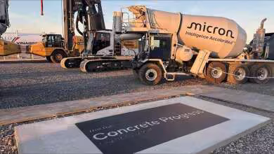 Camion toupie Micron « Intelligence Accelerated » sur chantier de béton, avec pelle mécanique et logo Concrete Progress