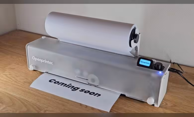Imprimante OpenPrinter transparente affichant une feuille “coming soon” et un écran de contrôle numérique.