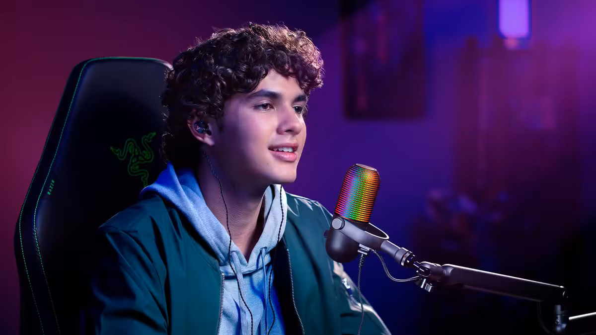 Jeune streamer utilisant un micro Razer Seiren V3 Chroma RGB sur bras articulé, ambiance gaming violette