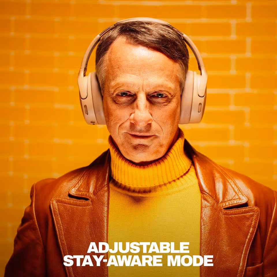 Skullcandy Crusher 1080 ANC : le casque à basses sensorielles s'allie aux technologies Bose 4 Personne portant un casque Skullcandy beige avec texte “Adjustable Stay-Aware Mode” en bas.