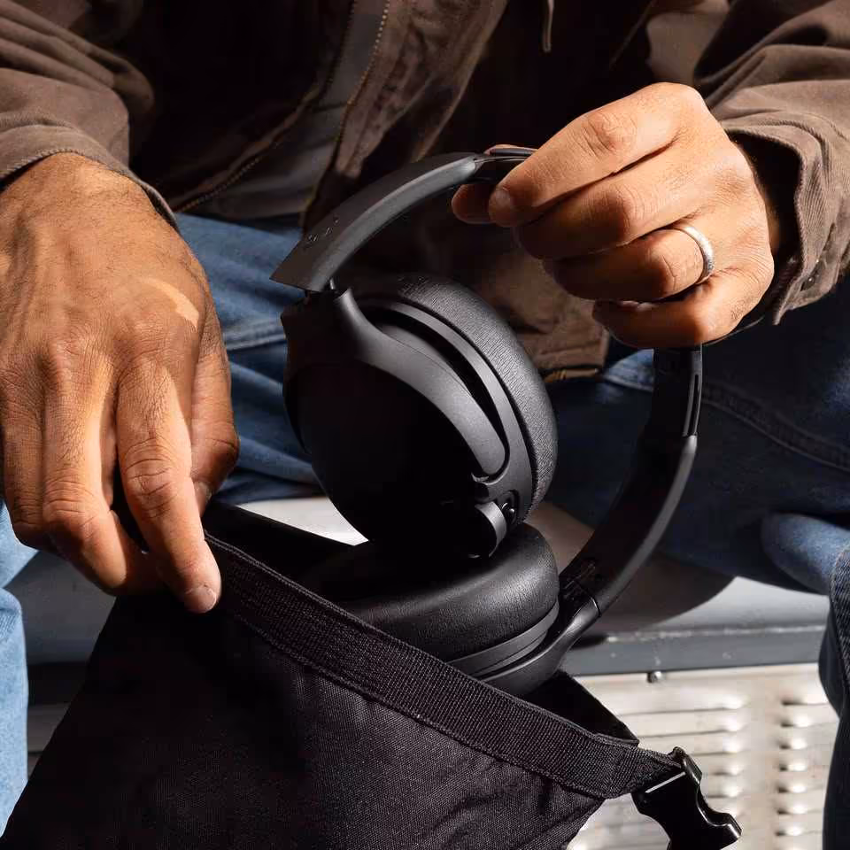 Skullcandy Crusher 1080 ANC : le casque à basses sensorielles s'allie aux technologies Bose 5 Casque Skullcandy noir plié dans un sac, tenu par une personne assise.