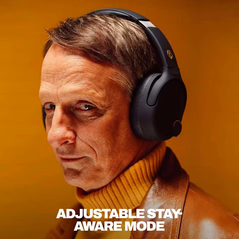 Skullcandy Crusher 720 : THX Spatial Audio, 65 h d’autonomie et basses réglables 7 Homme portant un casque Skullcandy noir, mode Stay Aware ajustable, fond orange