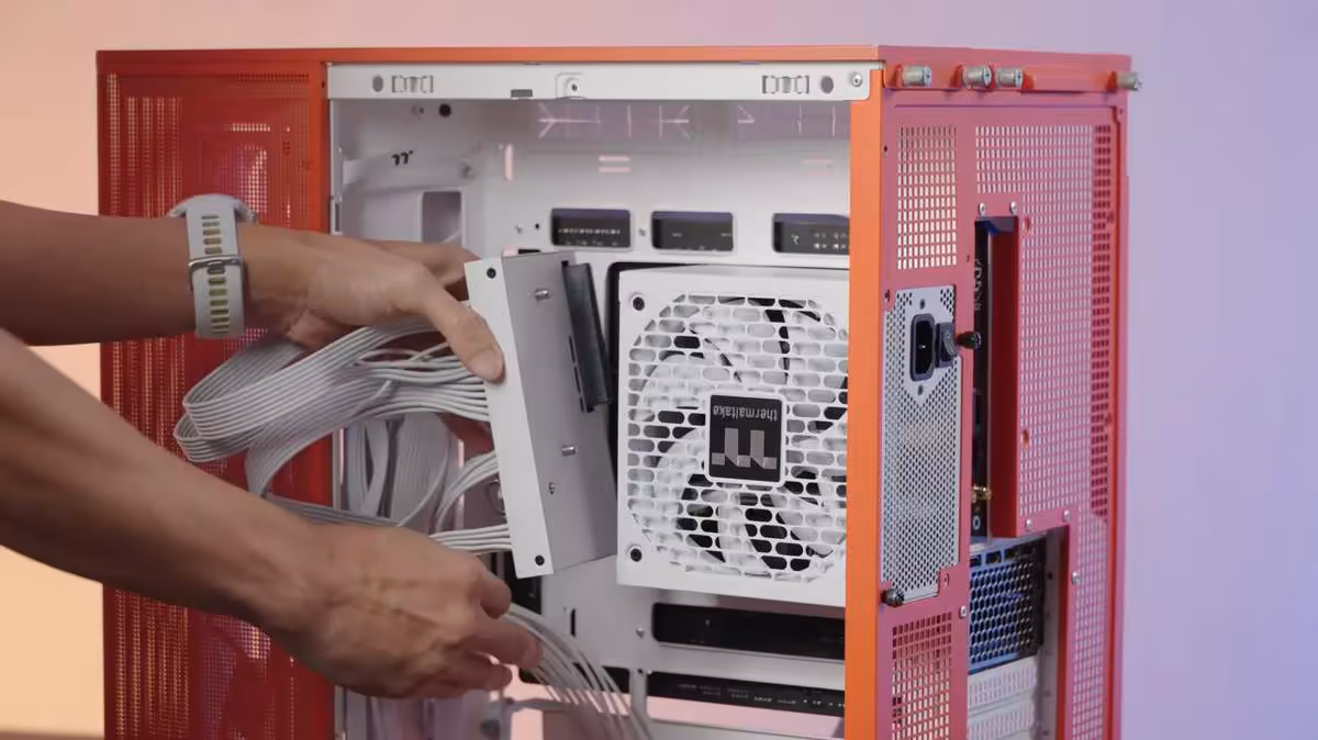 Dockpower FI : Thermaltake sépare le bloc et les câbles sur ses alimentations ATX 3.1 3 Installation alimentation Thermaltake dans boîtier rouge main intervenant