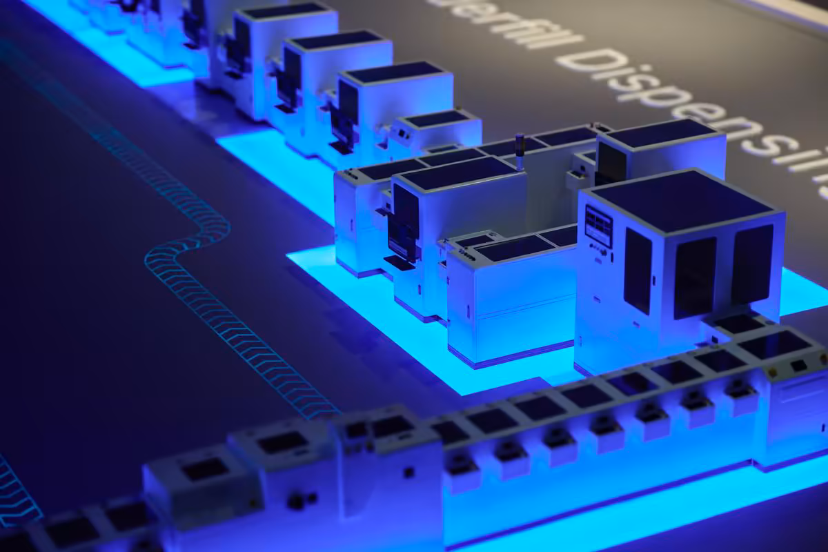 Apple Houston inaugure un centre industriel clé pour l'IA, les PME et le Mac mini 4 Maquette lumineuse d’une chaîne de production industrielle avec blocs métalliques et éclairage bleu.