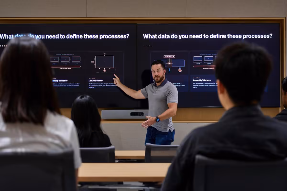 Apple Houston inaugure un centre industriel clé pour l'IA, les PME et le Mac mini 5 Présentateur expliquant un écran sur les processus de fabrication à un groupe en salle de réunion.