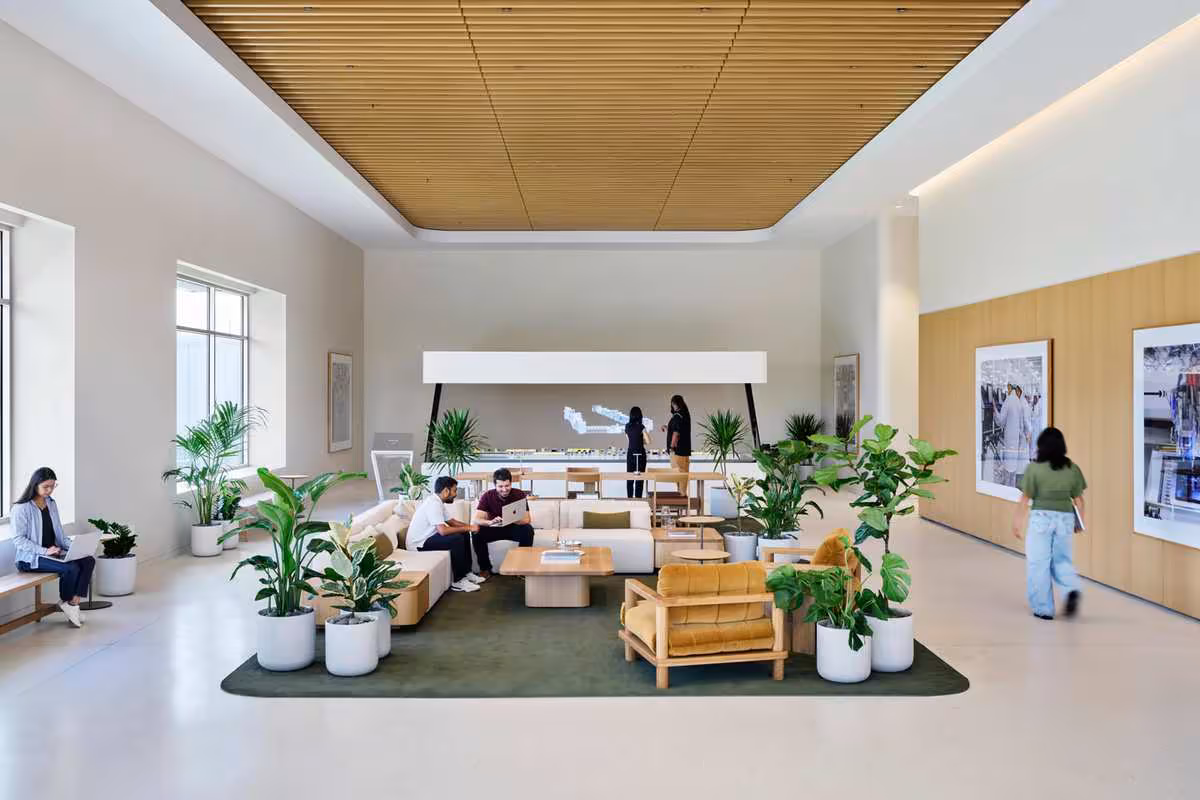 Apple Houston inaugure un centre industriel clé pour l'IA, les PME et le Mac mini 6 Espace lounge lumineux du centre Apple Houston avec canapés, plantes et grande présentation murale.