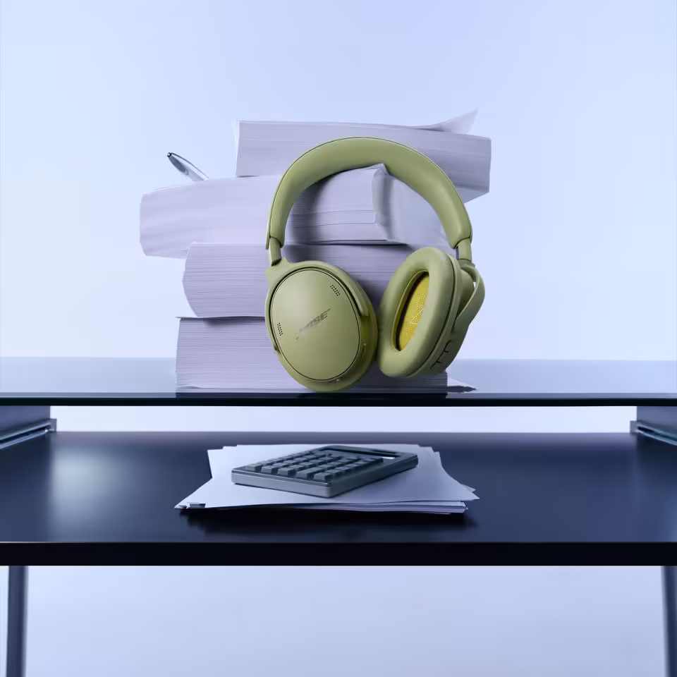 Casque Bose QuietComfort vert posé sur des livres, avec bureau et calculatrice en premier plan