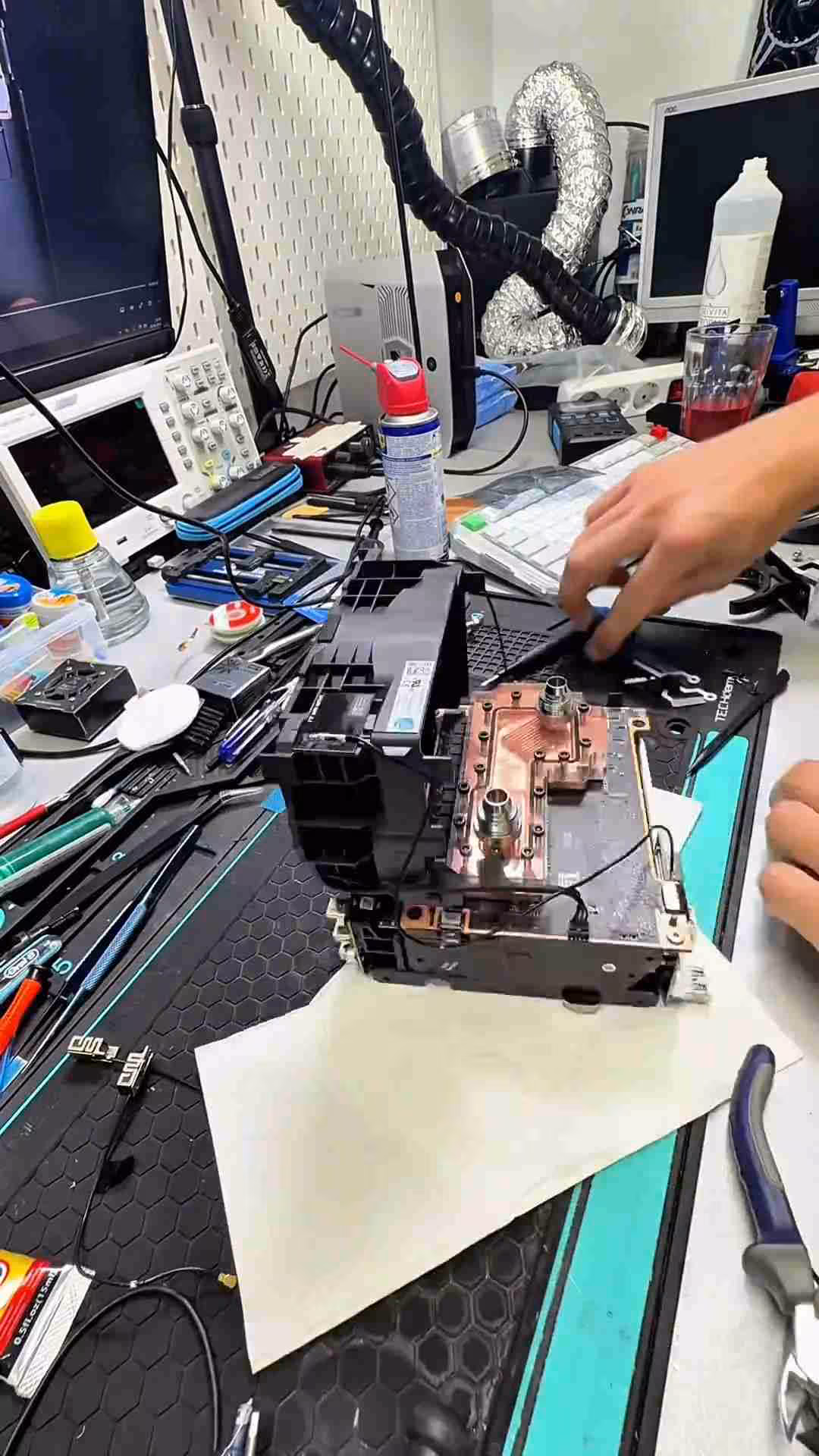 Atelier électronique avec matériel divers et mains ajustant composant, éclairage moyen.