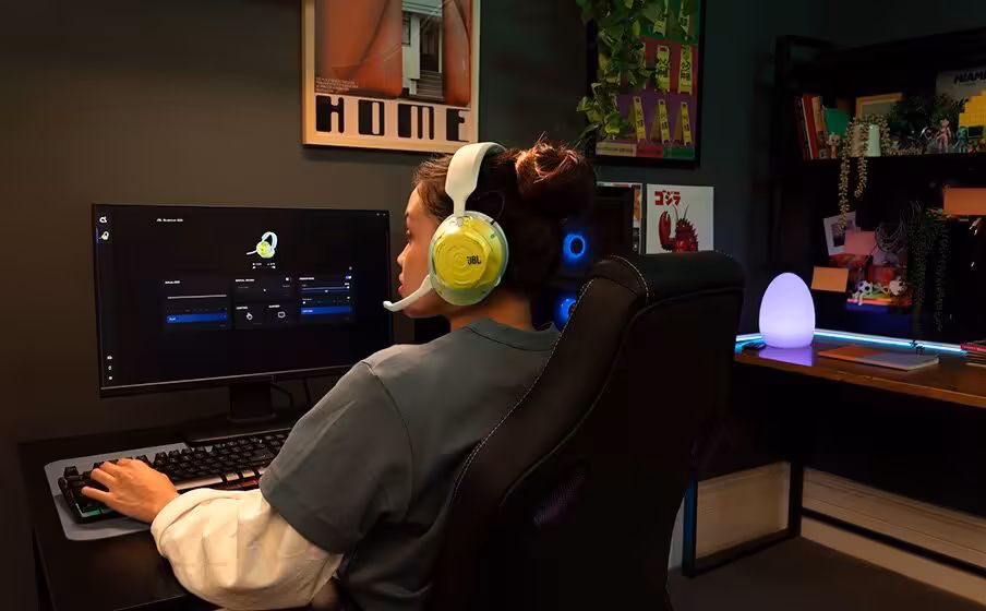 JBL Quantum 520 : la gamme gaming s’élargit avec les 520X et 120 dévoilés à la Gamescom 2026 8 Joueuse avec casque JBL jaune devant un écran PC, setup gaming de bureau.