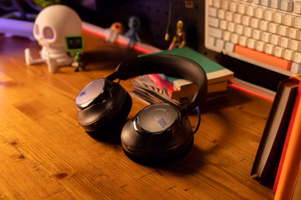 JBL Quantum 520 : la gamme gaming s’élargit avec les 520X et 120 dévoilés à la Gamescom 2026 2 Casque JBL noir posé sur un bureau en bois, photo lifestyle avec clavier et décoration en arrière-plan.