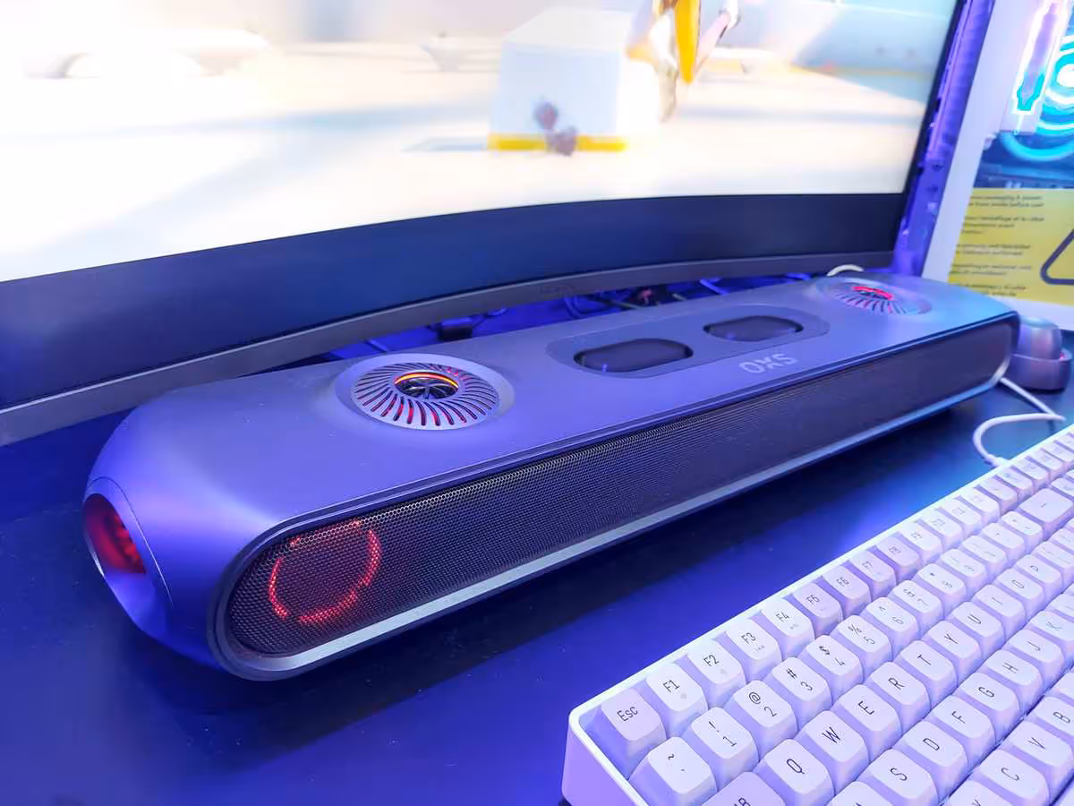 OXS Thunder Duo et Pro Max à la Gamescom 2026, l’Atmos PC passe par un haut-parleur de cou 7 Barre de son OXS Thunder Duo inclinée sous moniteur incurvé, éclairage RGB et clavier blanc