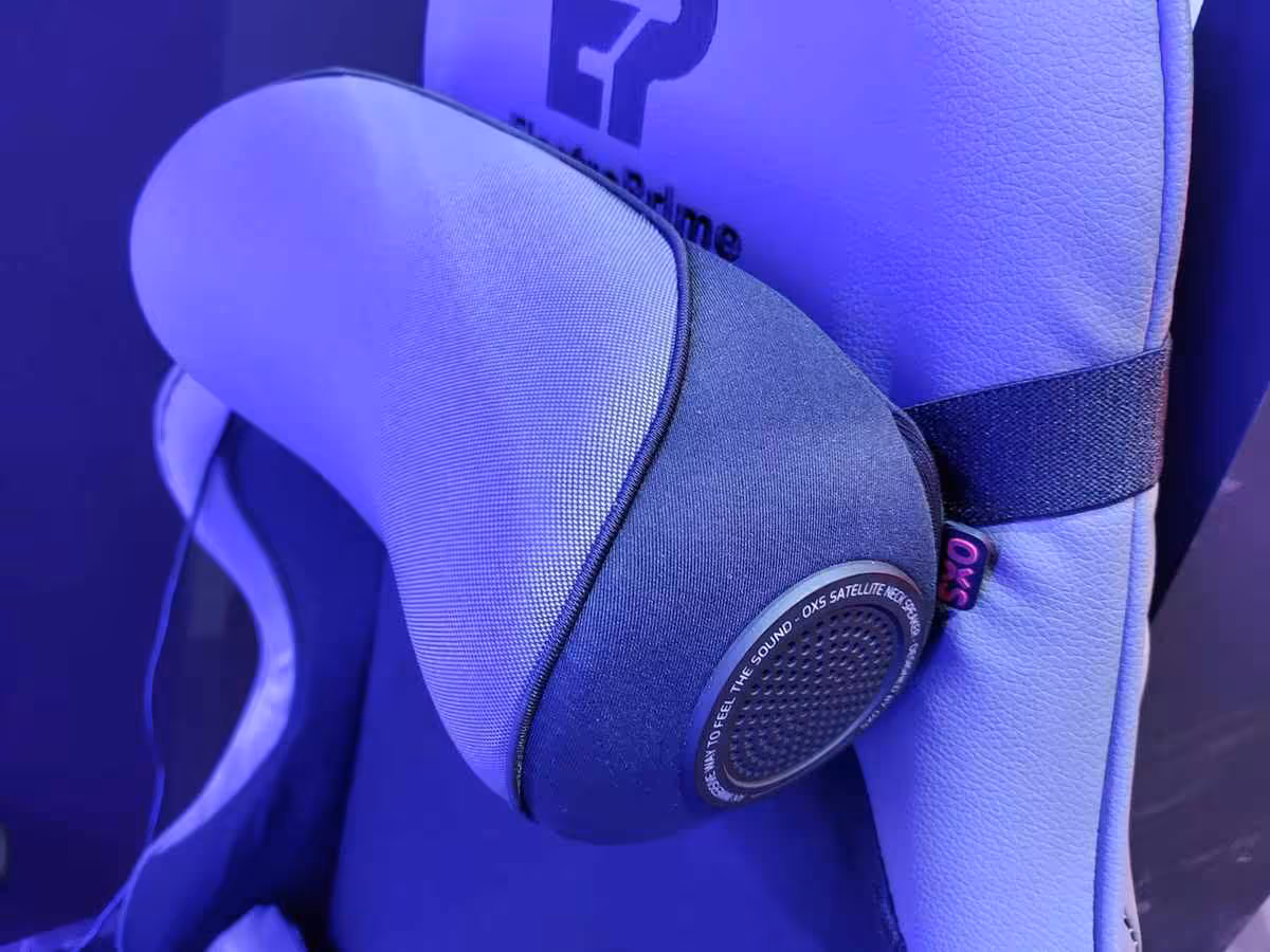 OXS Thunder Duo et Pro Max à la Gamescom 2026, l’Atmos PC passe par un haut-parleur de cou 2 Haut-parleur OXS compact de profil, fixé à l’arrière d’un siège gaming, éclairage violet ambiant