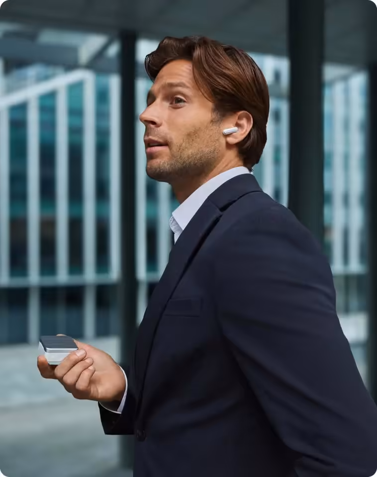 Plaud One Explorer Edition : des écouteurs IA autonomes avec eSIM 4G pour les pros 6 Homme en costume portant les écouteurs Plaud One et tenant le boîtier de recharge