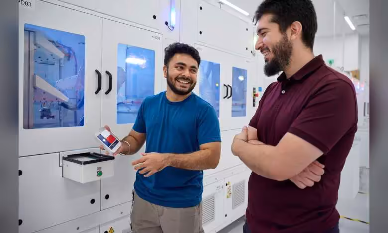 Apple Houston inaugure un centre industriel clé pour l'IA, les PME et le Mac mini 1 Deux employés souriants devant des machines automatisées, l’un tenant un badge ou smartphone Apple.