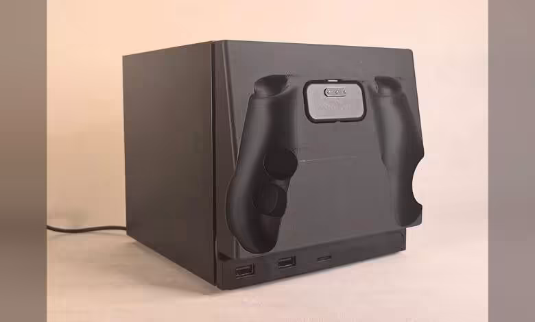 Steam Machine : une façade imprimée transforme l’avant en dock amovible pour Controller 1 Boîtier cube noir mat avec emplacement manettes, ports USB visible fond beige