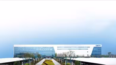 Siège moderne de CXMT avec façade vitrée blanche et logo bleu, devant une esplanade paysagée
