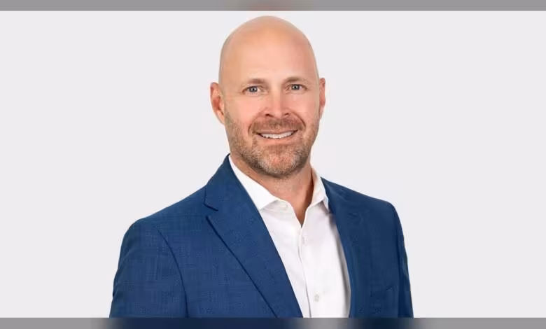 Dean Jarnac rejoint Intel comme chief sales officer pour piloter la relance commerciale 1 Portrait studio de Dean Jarnac, homme chauve en costume bleu et chemise blanche, fond blanc neutre