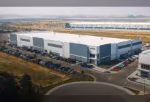Grand bâtiment industriel Micron blanc et gris, parking rempli, vue aérienne du centre de formation techno