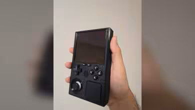 Console portable SteamBoy tenue en main avec écran noir et boutons sur fond neutre