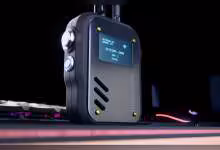 TACCOM v2 noir avec écran OLED, boutons latéraux et LED, photographié sur bureau gaming