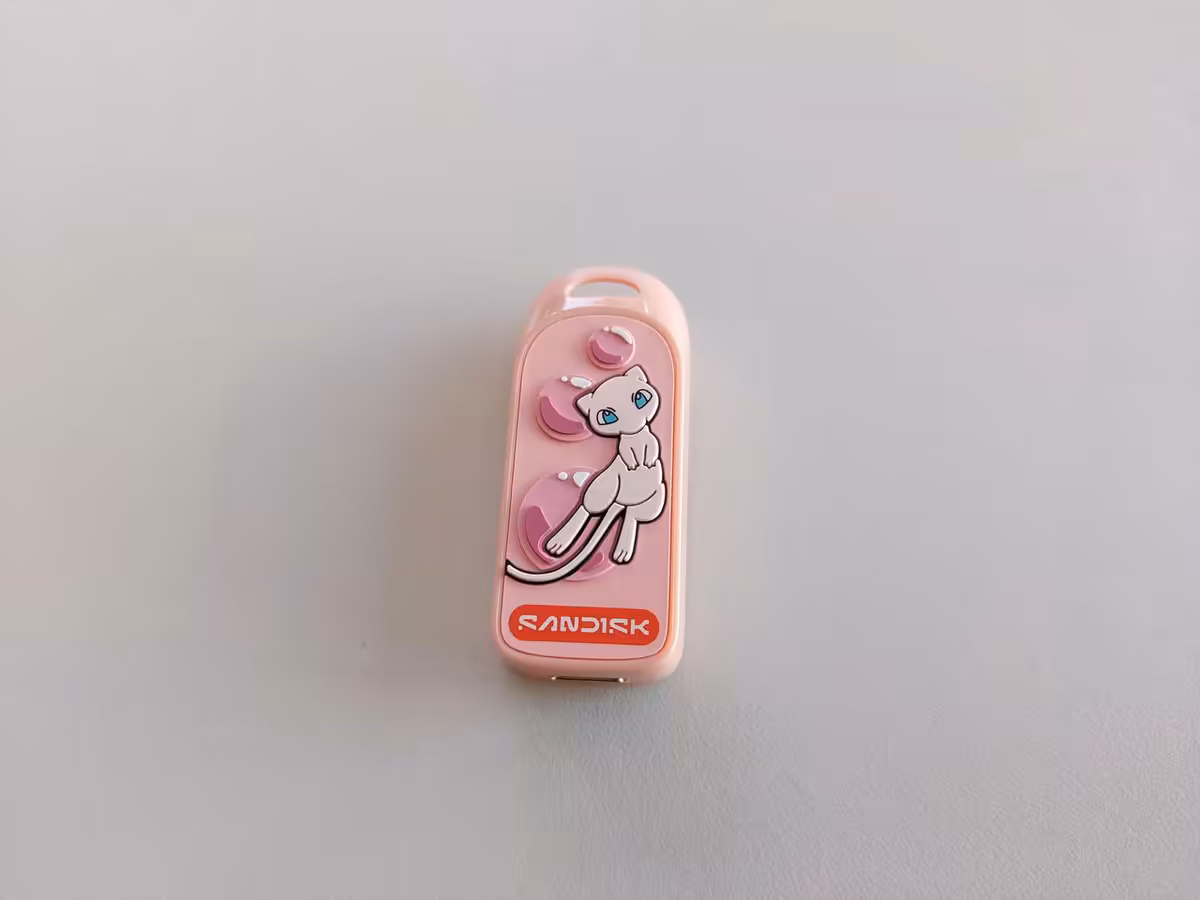 Sandisk Pokémon : deux stockages collector pour les 30 ans de la licence à la Gamescom 2026 2 Clé USB SanDisk rose avec illustration de Mew, vue de face sur fond clair