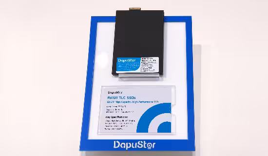 SSD DapuStor : 512 To et refroidissement liquide pour l’IA dévoilés au FMS 2026 6 SSD DapuStor R6011 TLC SSD sur fond bleu, vue de dessus avec étiquette produit