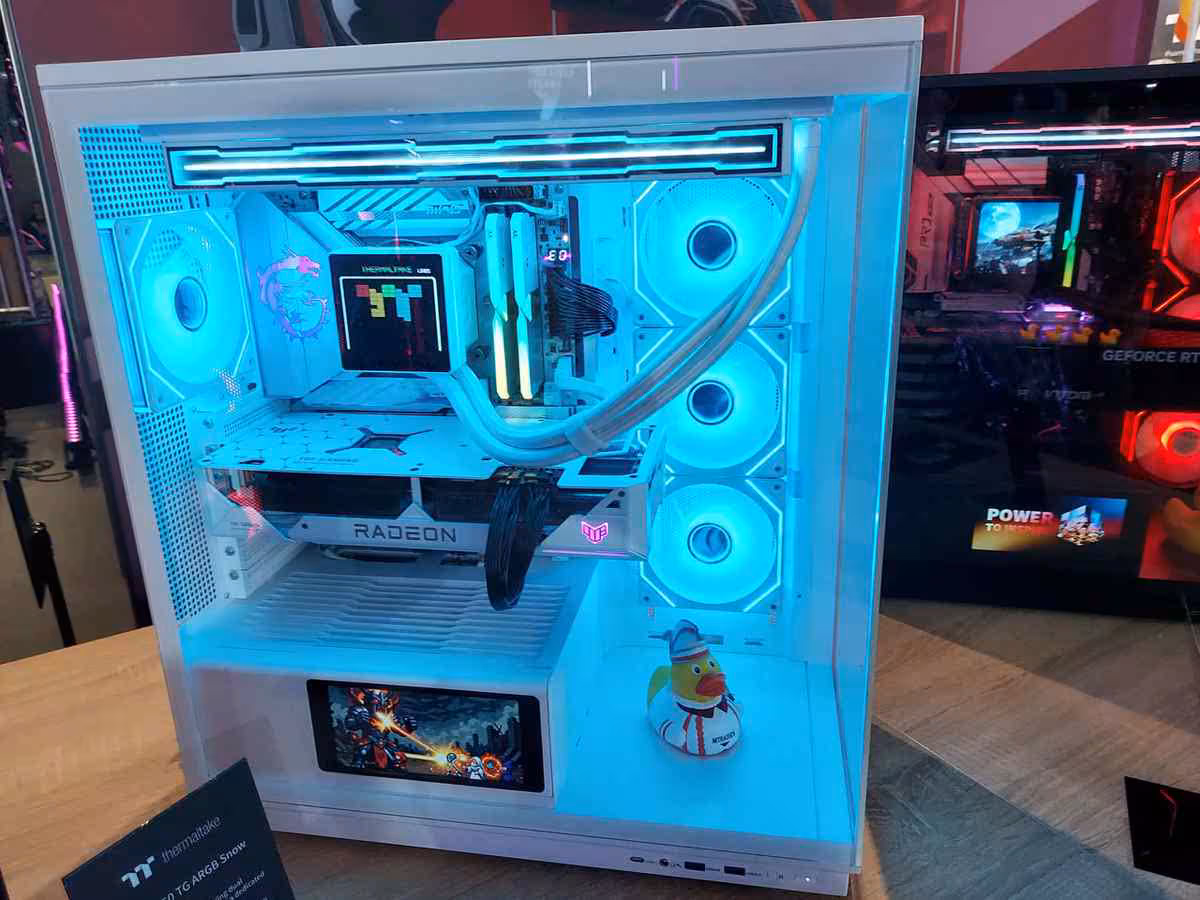 Thermaltake Gamescom 2026 : CAPO X, Stage 450 TG et alimentations DockPower 4 Boîtier blanc vitré avec carte Radeon, refroidissement liquide et écran secondaire intégré.